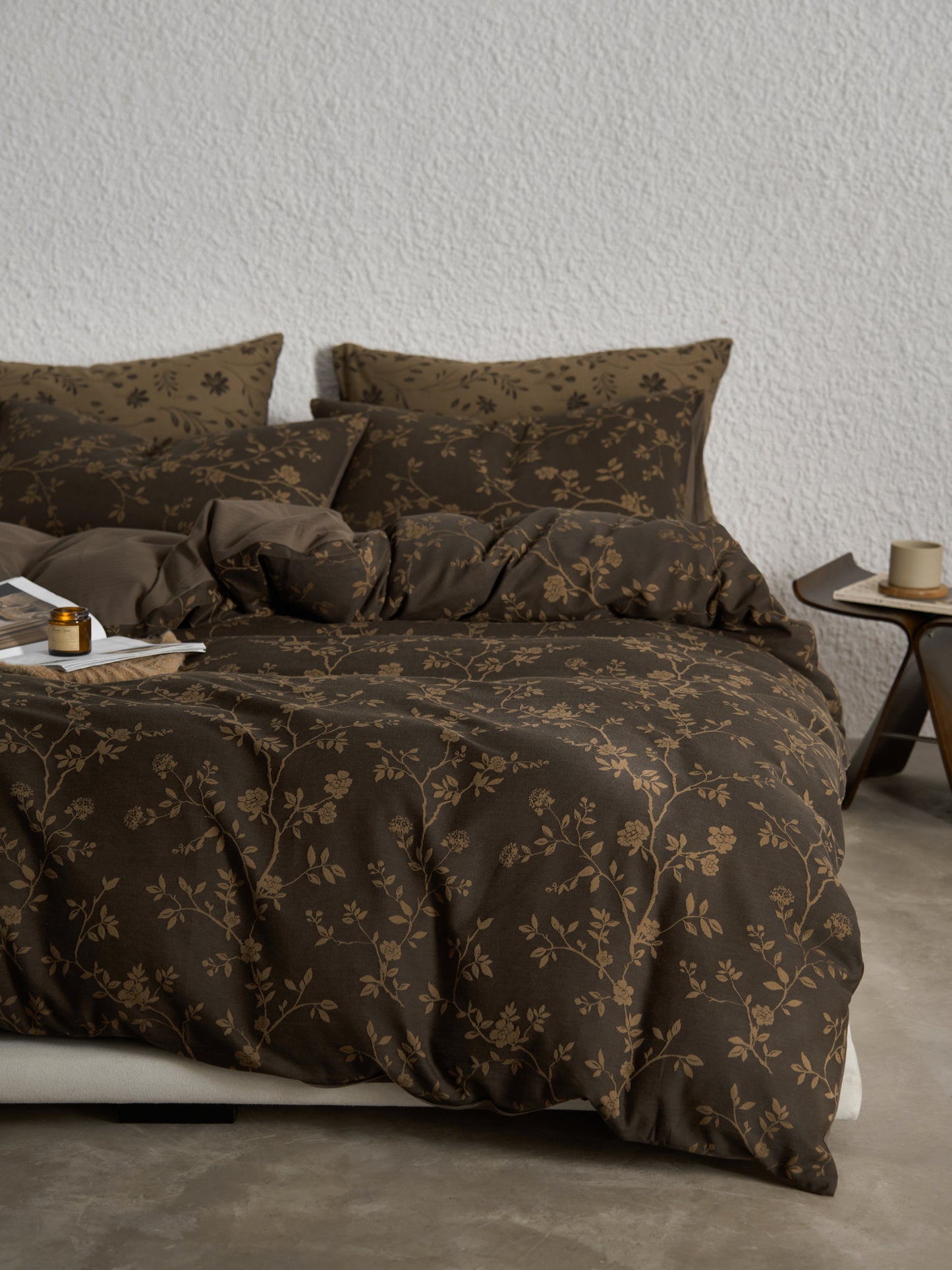 A cozy bed adorned with a brown duvet cover featuring a delicate small floral pattern, complemented by a matching bed sheet and pillowcases for a warm and inviting look.