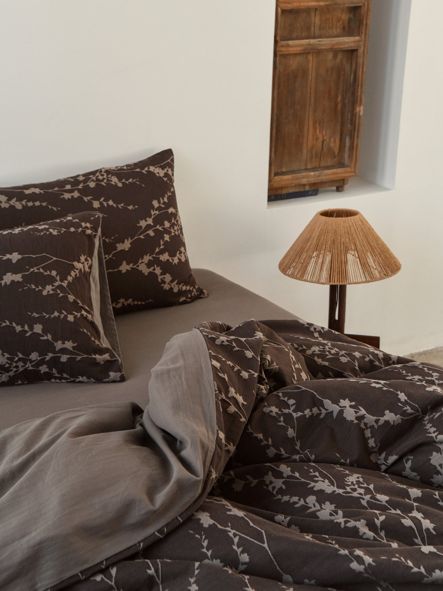 Taupe vine bedding set on a cozy bed with decorative pillows and a stylish lamp, creating an organic sophisticated ambiance.