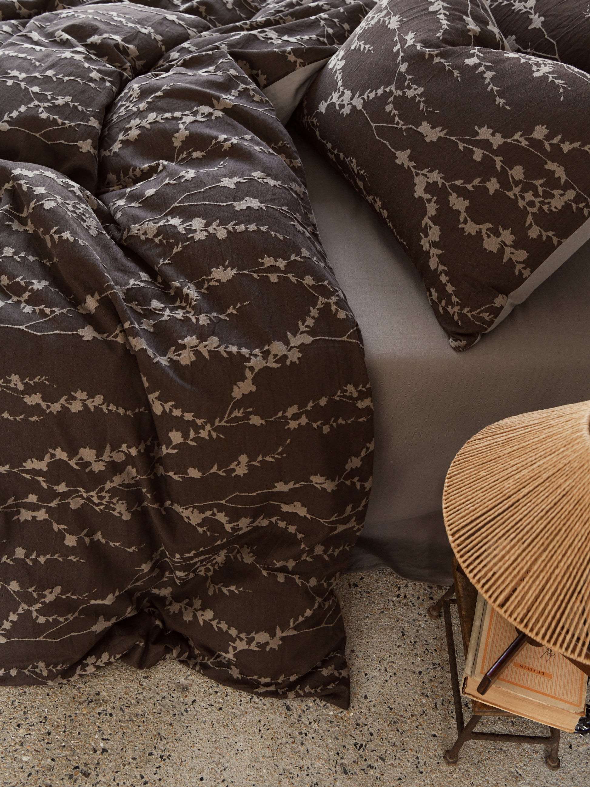 Taupe vine bedding set featuring elegant leaf patterns on a dark background, styled with a cozy decor arrangement.